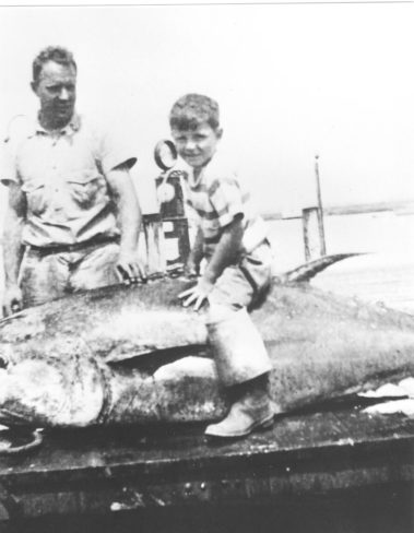 Bob and his father trying to fill his boots on top of a tuna. Roughly 1939.